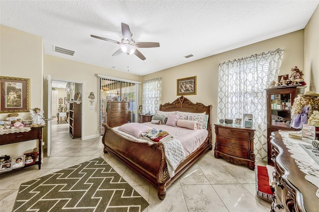 bedroom with tile patterned flooring, a ceiling fan, a textured ceiling, and visible vents
