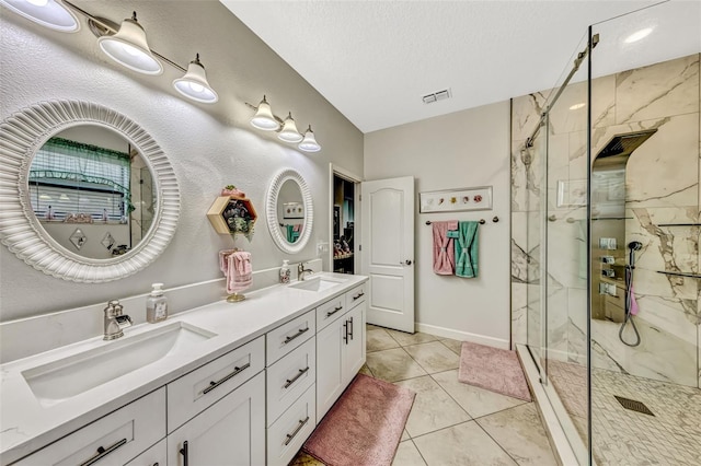 full bath featuring double vanity, visible vents, a marble finish shower, and a sink