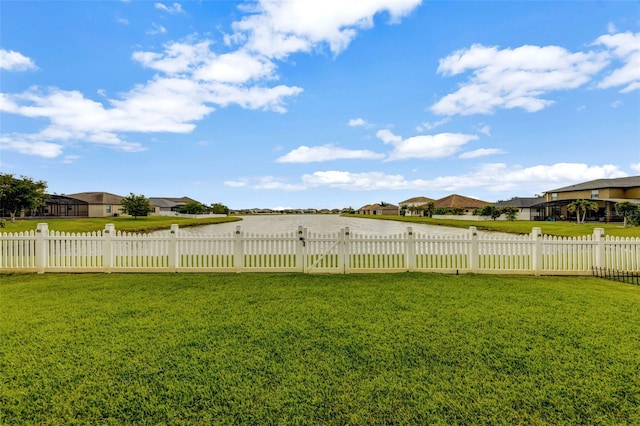 view of yard featuring fence, a water view, and a residential view