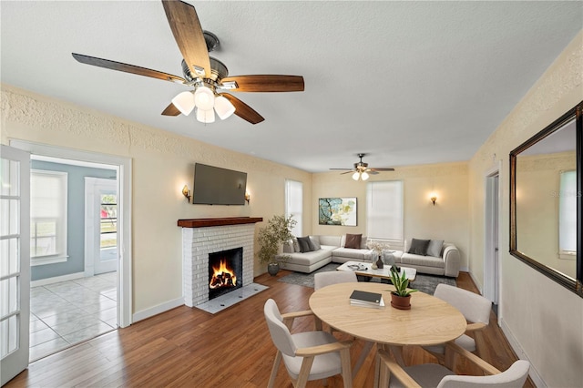 1400 Florida Ave, Saint Cloud, FL 34769 - dining room featuring light wood-style floors, ceiling fan, a fireplace, baseboards, and a textured ceiling