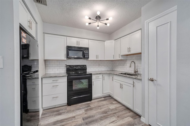kitchen with a sink, a textured ceiling, black appliances, and white cabinetry