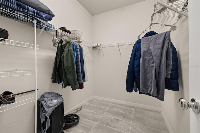 walk in closet featuring marble finish floor