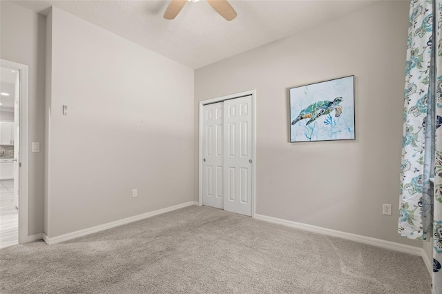 unfurnished bedroom featuring a ceiling fan, baseboards, light carpet, and a closet