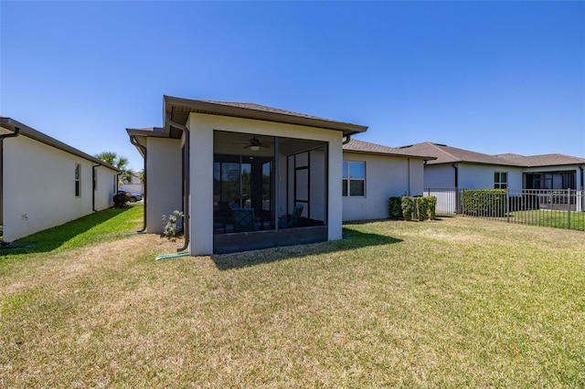 rear view of property with fence, stucco siding, a sunroom, ceiling fan, and a lawn
