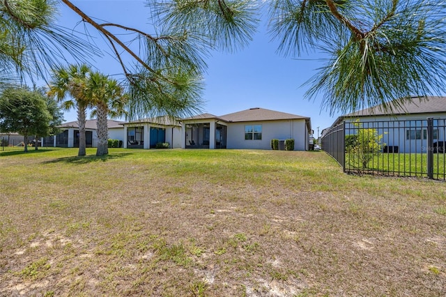 back of house featuring fence, stucco siding, and a yard