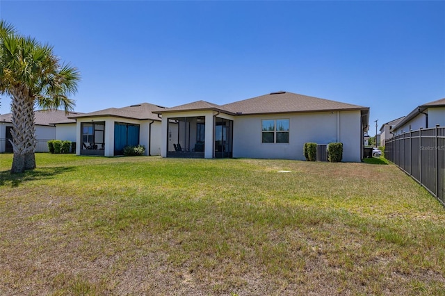 back of property with fence, a lawn, stucco siding, and a sunroom