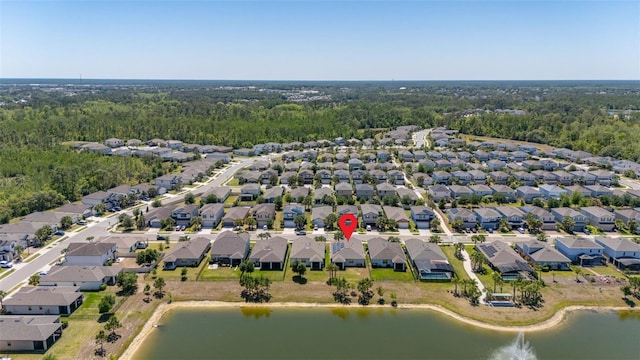 drone / aerial view with a wooded view, a water view, and a residential view