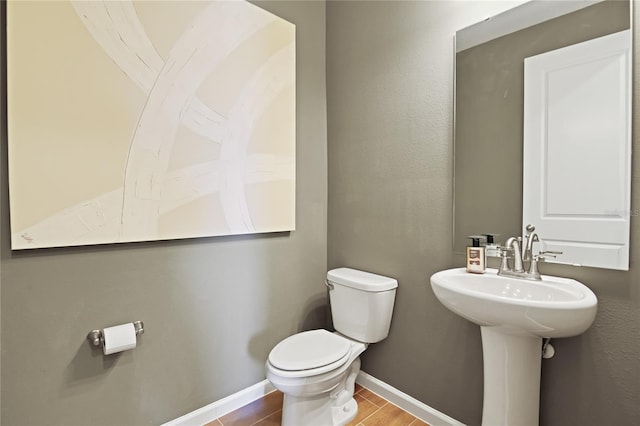 bathroom with toilet, baseboards, and wood finished floors