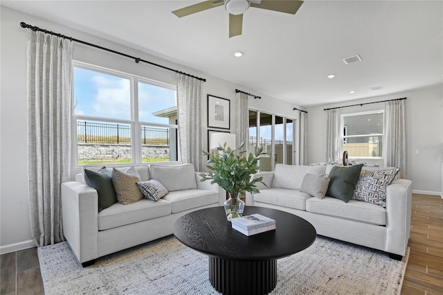 living area with visible vents, baseboards, ceiling fan, and wood finished floors