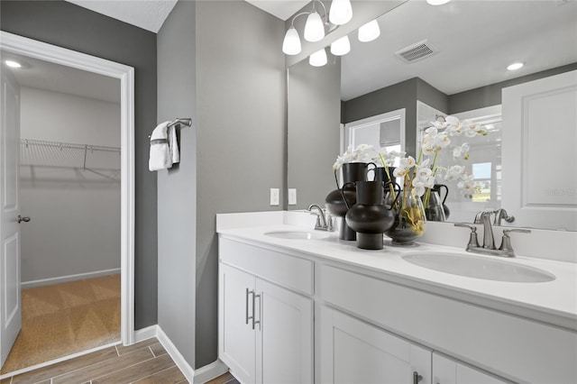 bathroom with visible vents, a sink, a spacious closet, and wood finished floors