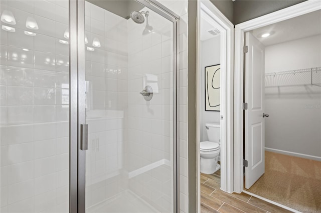 bathroom with toilet, visible vents, a walk in closet, and a stall shower