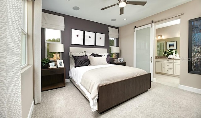 bedroom featuring multiple windows, a barn door, baseboards, light carpet, and ensuite bath