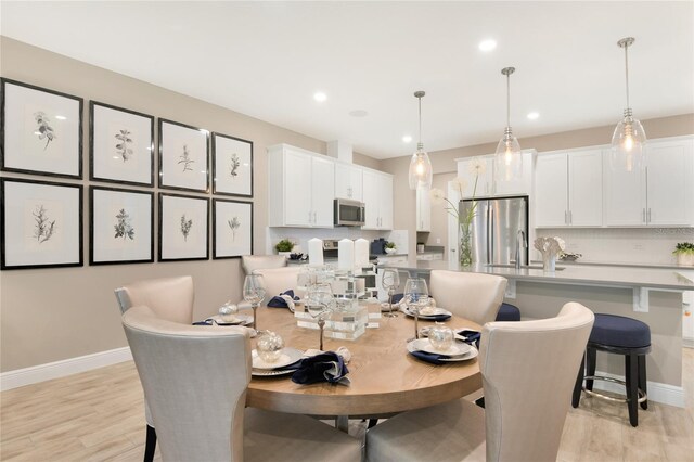 dining room featuring light wood-style floors, recessed lighting, and baseboards