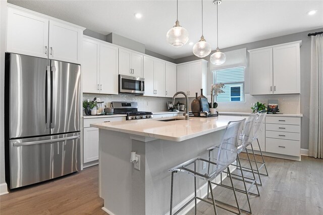 kitchen featuring a sink, appliances with stainless steel finishes, backsplash, and light wood-type flooring