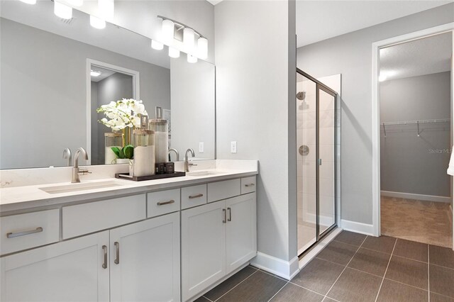 full bath with a sink, a walk in closet, a stall shower, and double vanity