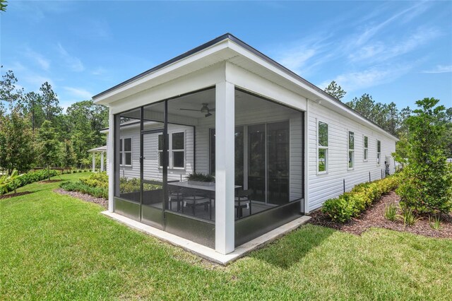 back of property with a yard, ceiling fan, and a sunroom