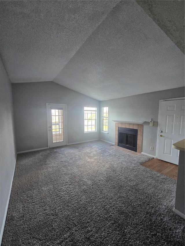 4301 Lizshire Ln Unit 306, Orlando, FL 32822 - unfurnished living room with carpet flooring, vaulted ceiling, baseboards, a tiled fireplace, and a textured ceiling
