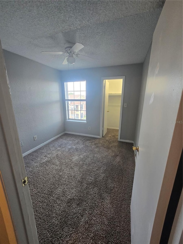 4301 Lizshire Ln Unit 306, Orlando, FL 32822 - unfurnished bedroom with baseboards, carpet, a spacious closet, a ceiling fan, and a textured ceiling