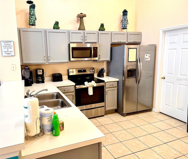 314 Saddle Ridge Dr, Davenport, FL 33896 - kitchen featuring appliances with stainless steel finishes, a sink, light countertops, light tile patterned floors, and gray cabinetry