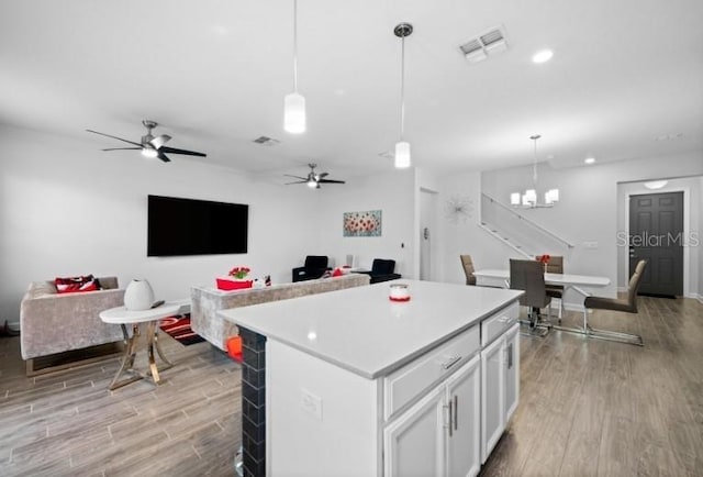 1231 Sandwedge St, Davenport, FL 33896 - kitchen featuring visible vents, a kitchen island, open floor plan, white cabinetry, and light wood-style flooring