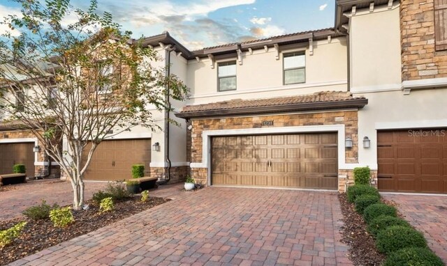 1231 Sandwedge St, Davenport, FL 33896 - view of front of house featuring an attached garage, decorative driveway, stucco siding, and stone siding