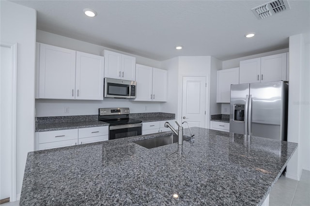 2189 Teneroc Trl, Lakeland, FL 33801 - kitchen featuring white cabinets, appliances with stainless steel finishes, a sink, dark stone counters, and visible vents