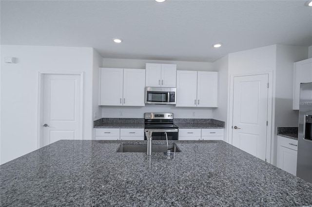 2189 Teneroc Trl, Lakeland, FL 33801 - kitchen featuring dark stone counters, white cabinetry, appliances with stainless steel finishes, and recessed lighting
