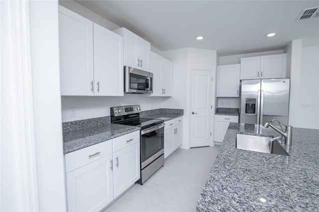 2189 Teneroc Trl, Lakeland, FL 33801 - kitchen featuring visible vents, a sink, dark stone countertops, stainless steel appliances, and white cabinetry