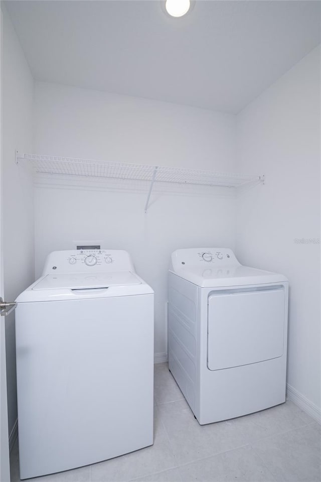 2189 Teneroc Trl, Lakeland, FL 33801 - clothes washing area with light tile patterned floors, baseboards, laundry area, and washing machine and clothes dryer
