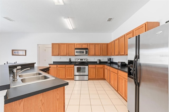kitchen with visible vents, appliances with stainless steel finishes, dark countertops, a sink, and light tile patterned floors