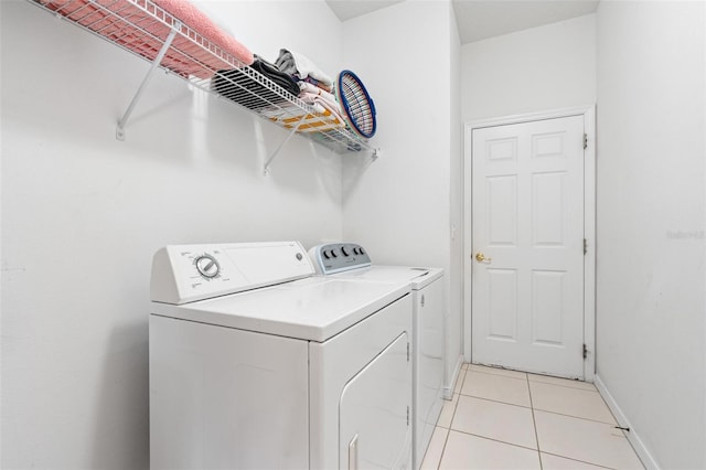 washroom with laundry area, baseboards, light tile patterned flooring, and washer and dryer