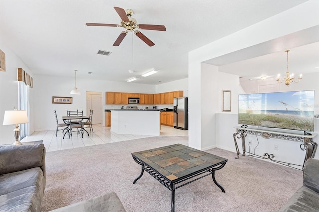 living area with light colored carpet, visible vents, and ceiling fan with notable chandelier