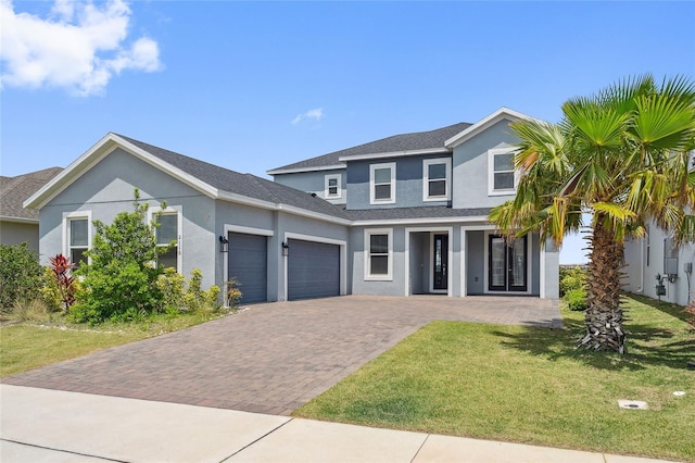 traditional-style home with roof with shingles, a front lawn, a garage, stucco siding, and decorative driveway