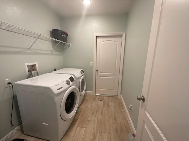 washroom featuring washing machine and clothes dryer, laundry area, baseboards, and light wood-style floors