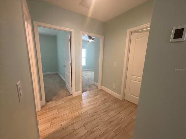 hallway with baseboards, visible vents, and wood finish floors