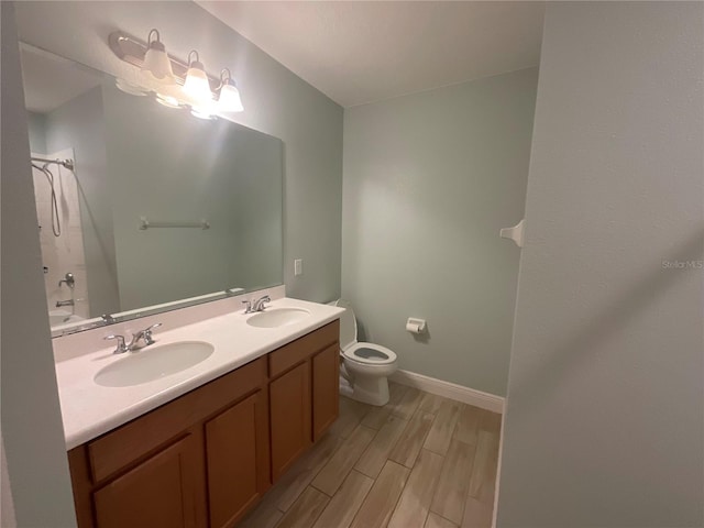 bathroom featuring a sink, toilet, baseboards, and wood finish floors