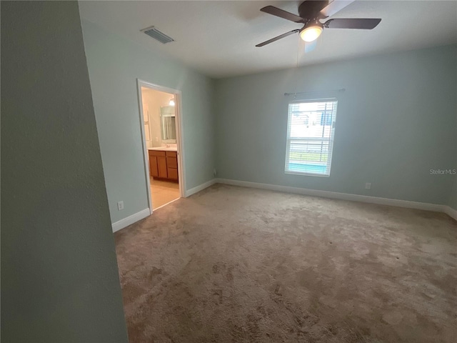 unfurnished bedroom featuring visible vents, light carpet, a ceiling fan, connected bathroom, and baseboards