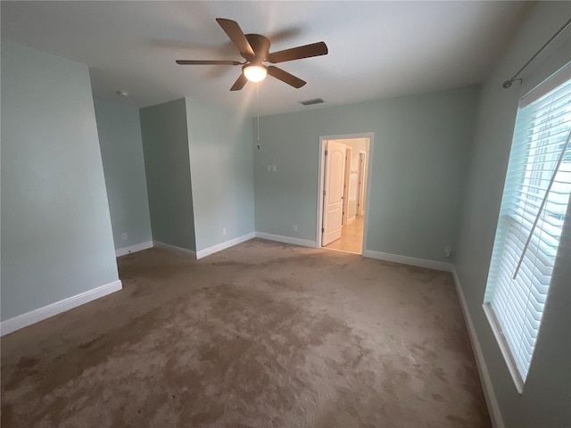 carpeted empty room with a ceiling fan, baseboards, and visible vents