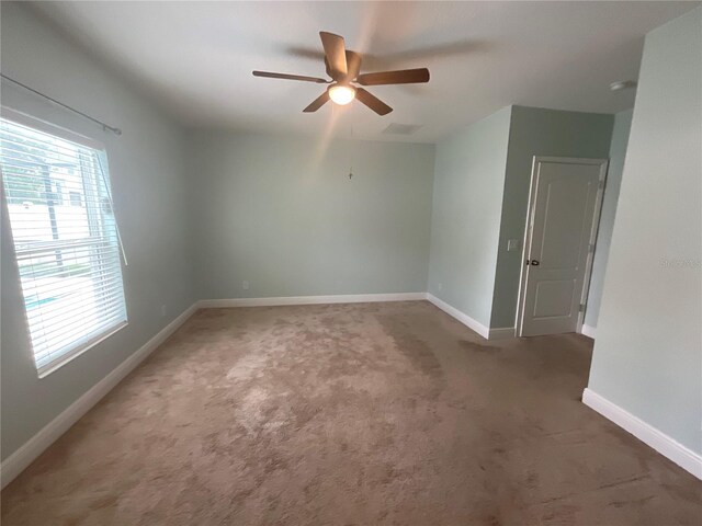 carpeted empty room featuring baseboards, visible vents, and ceiling fan