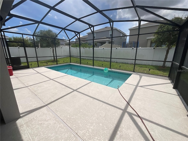view of pool with a lawn, a fenced in pool, a patio area, glass enclosure, and a fenced backyard