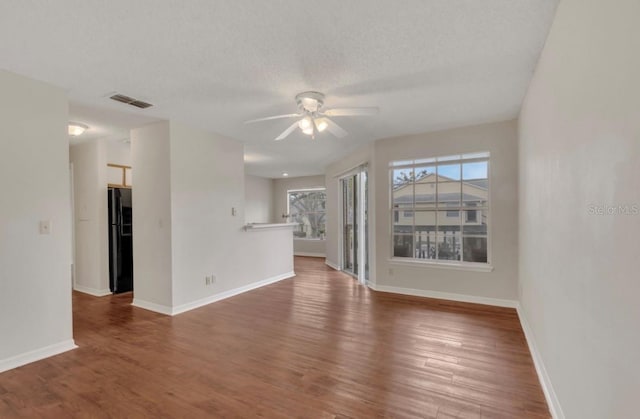 unfurnished living room with baseboards, a ceiling fan, wood finished floors, and visible vents