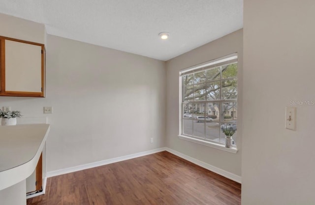 unfurnished dining area featuring baseboards and wood finished floors