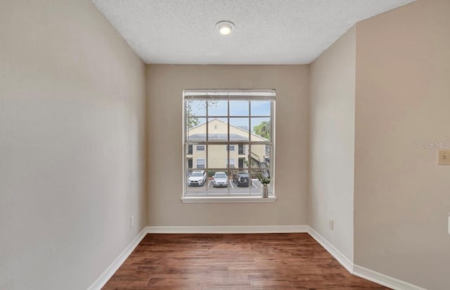 unfurnished room featuring baseboards, a textured ceiling, and wood finished floors