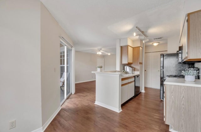 kitchen featuring light countertops, a peninsula, wood finished floors, and dishwasher