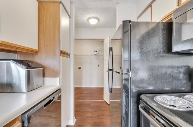 kitchen featuring a textured ceiling, freestanding refrigerator, wood finished floors, range with electric stovetop, and dishwashing machine