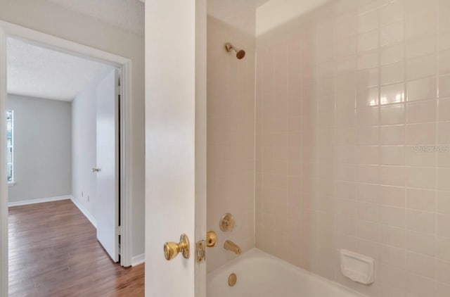 full bathroom featuring baseboards, shower / bathing tub combination, and wood finished floors