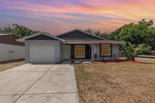 ranch-style house featuring an attached garage, a porch, driveway, a lawn, and stucco siding