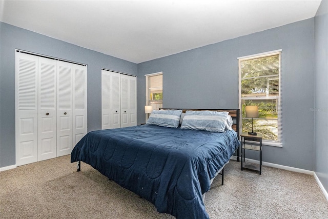 carpeted bedroom featuring two closets and baseboards