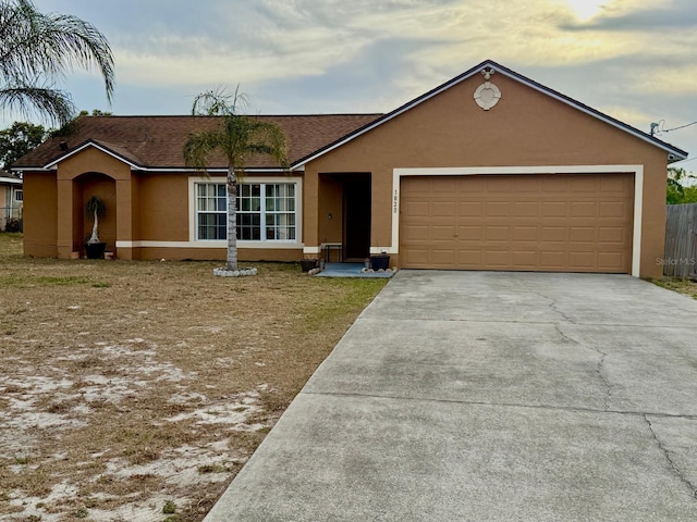 ranch-style home with roof with shingles, stucco siding, an attached garage, and driveway