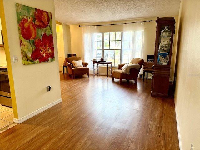 sitting room featuring baseboards, a textured ceiling, and wood finished floors